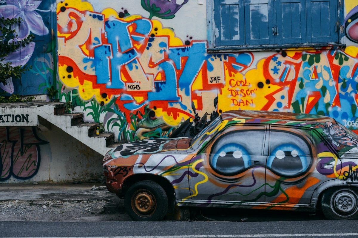 a car parked in front of a wall covered in graffiti