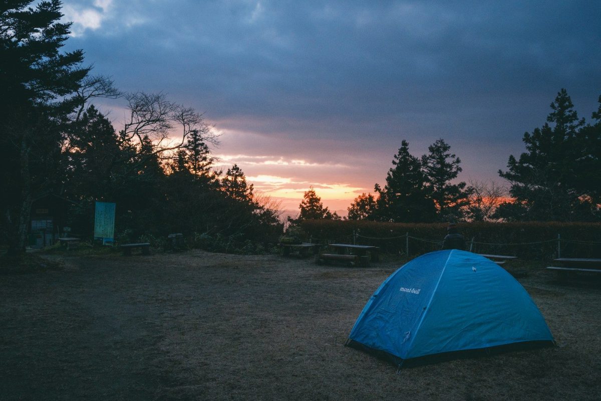 a blue tent sitting in the middle of a field