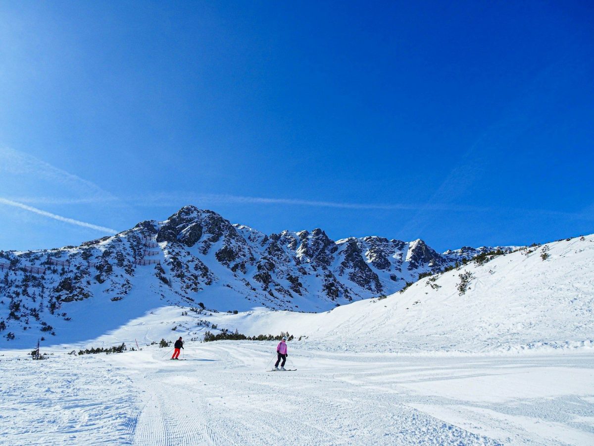 a couple of people riding skis down a snow covered slope