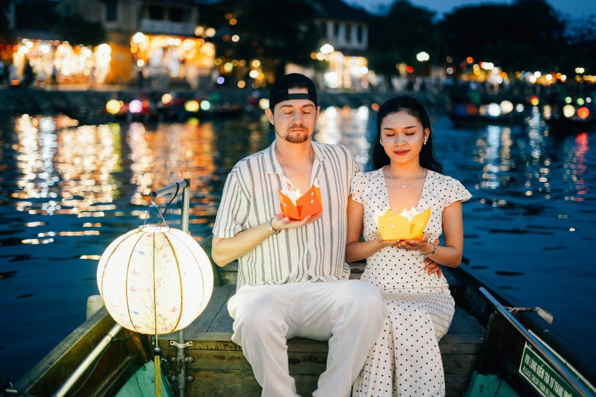 Couple holding lanterns on a boat at night