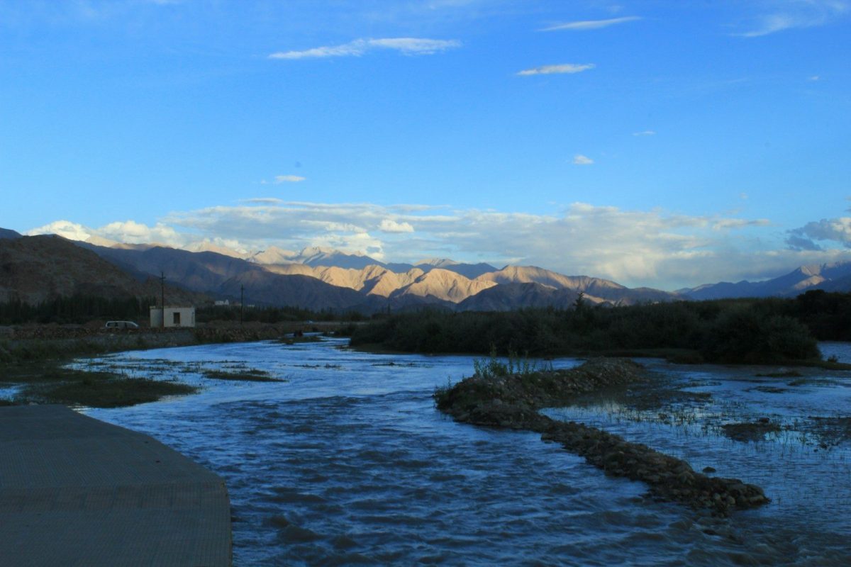 A wide river flows through a valley with mountains.