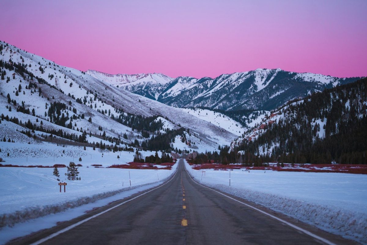 Empty road through snow-covered mountains at dusk