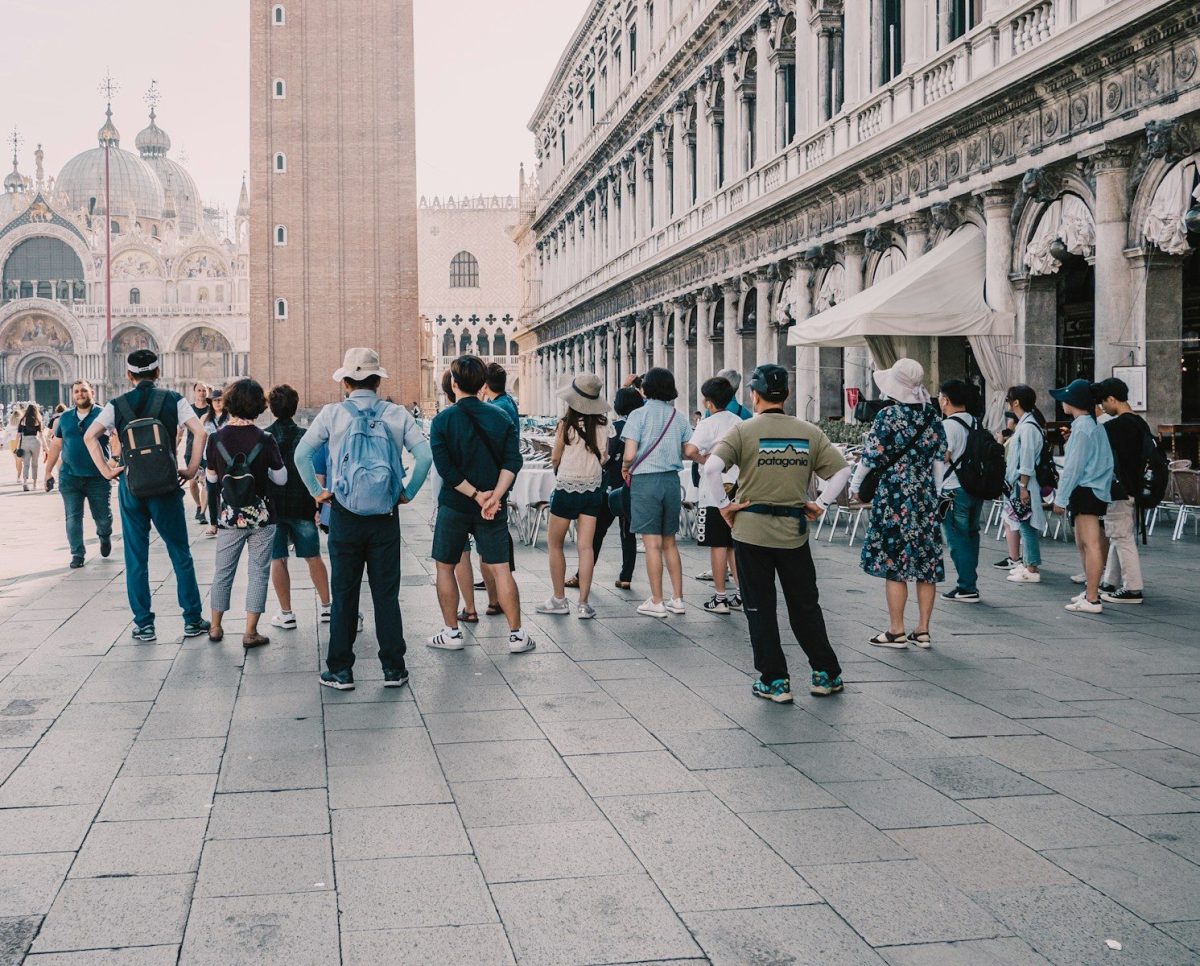 9 Behaviors Locals Hate About Tourists 7 a group of people standing on a street next to a tall building