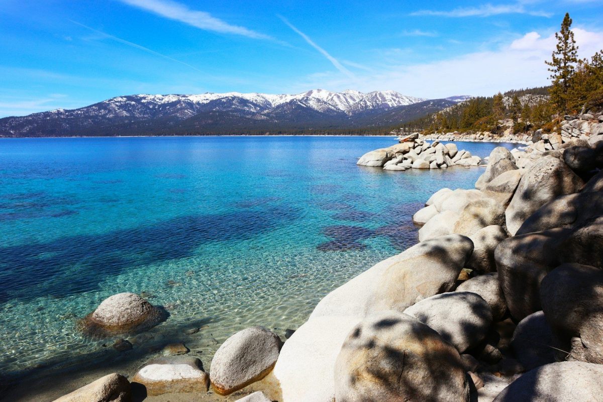 8 Must-Visit Lake Destinations in the U.S. for Summer Travelers 1 a rocky shore with clear blue water and mountains in the background