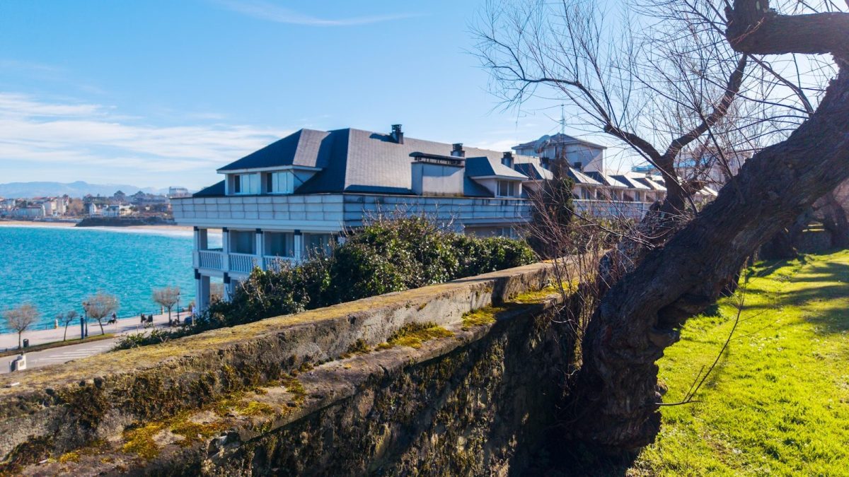 9 Beautiful Lakeside Homes Around the World Worth Seeing 5 Modern building overlooking a blue ocean with trees.