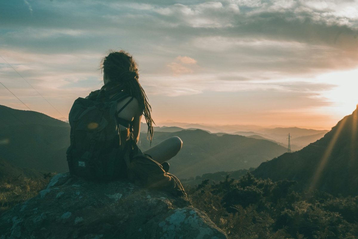 9 Essential Safety Tips for Solo Travelers 7 woman sitting on rock carrying black backpack