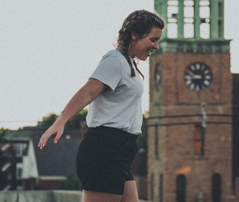 woman in white shirt and black shorts standing on gray concrete pavement during daytime
