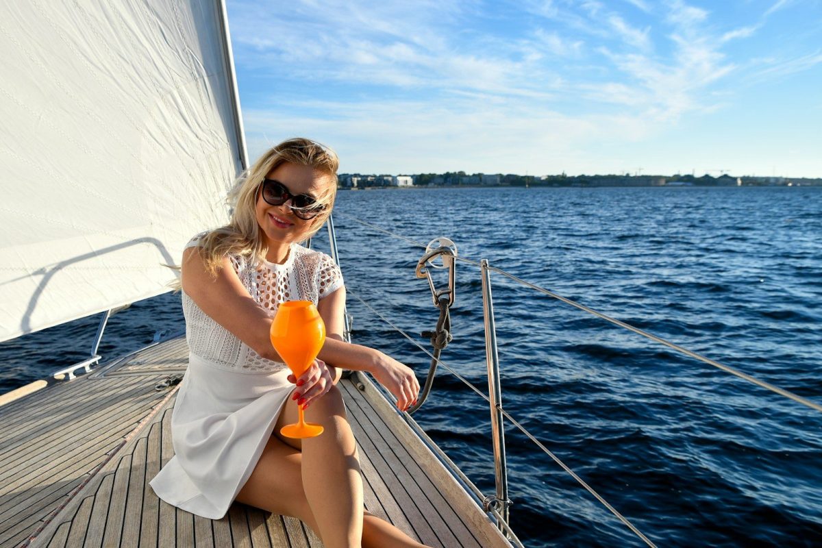 A woman enjoys a drink on a sailboat.