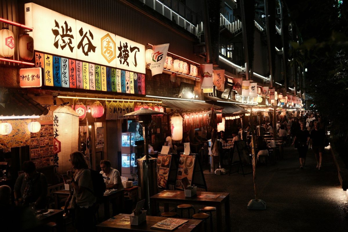 A group of people standing outside of a restaurant at night