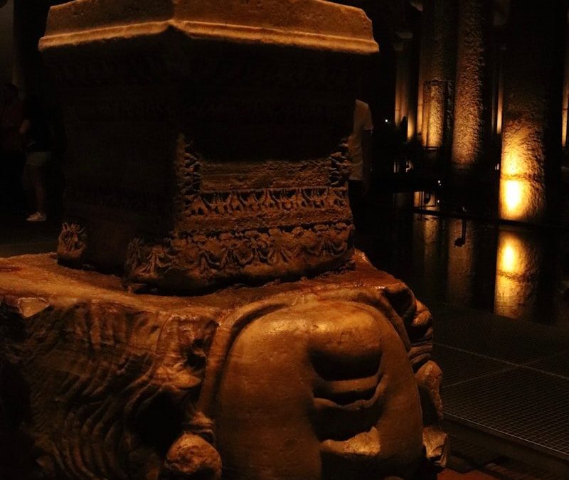 Stone column base with medusa head carving.