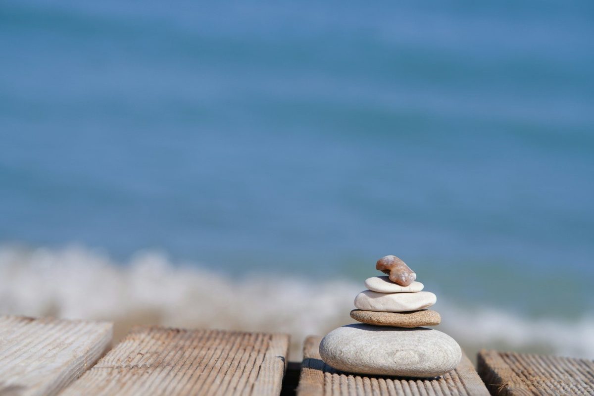 5 Luxury Wellness Retreats in the U.S. for Rest, Focus, and Mental Clarity 6 Stacked stones on a wooden pier with ocean waves.