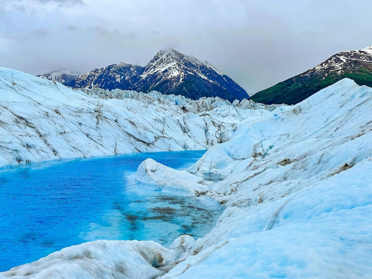 a blue lake surrounded by snow covered mountains