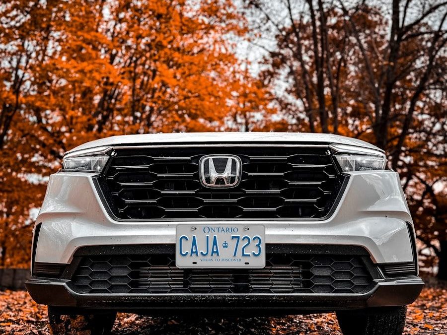 the front end of a white honda cr - v parked on a leaf covered road