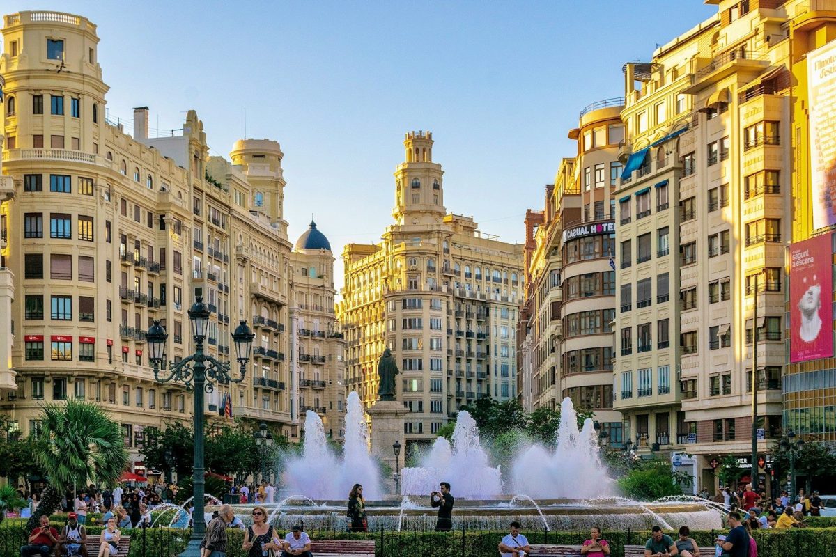 A group of people standing around a fountain in a city
