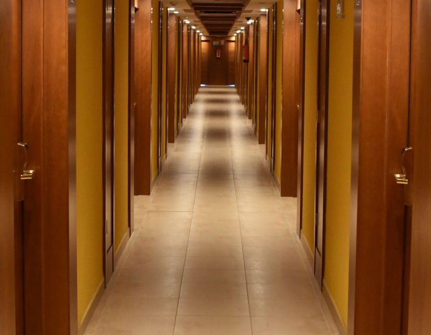 5 Hotel Room Locations You May Regret More Than a Bad View 1 Long hallway view of a modern hotel with wooden doors and ceiling, creating a luxurious ambiance.