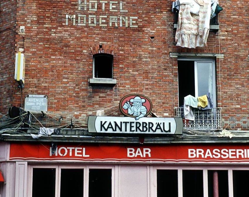 5 Hotel Room Locations You May Regret More Than a Bad View 2 Street view of a brick hotel exterior with prominent signage and open windows.