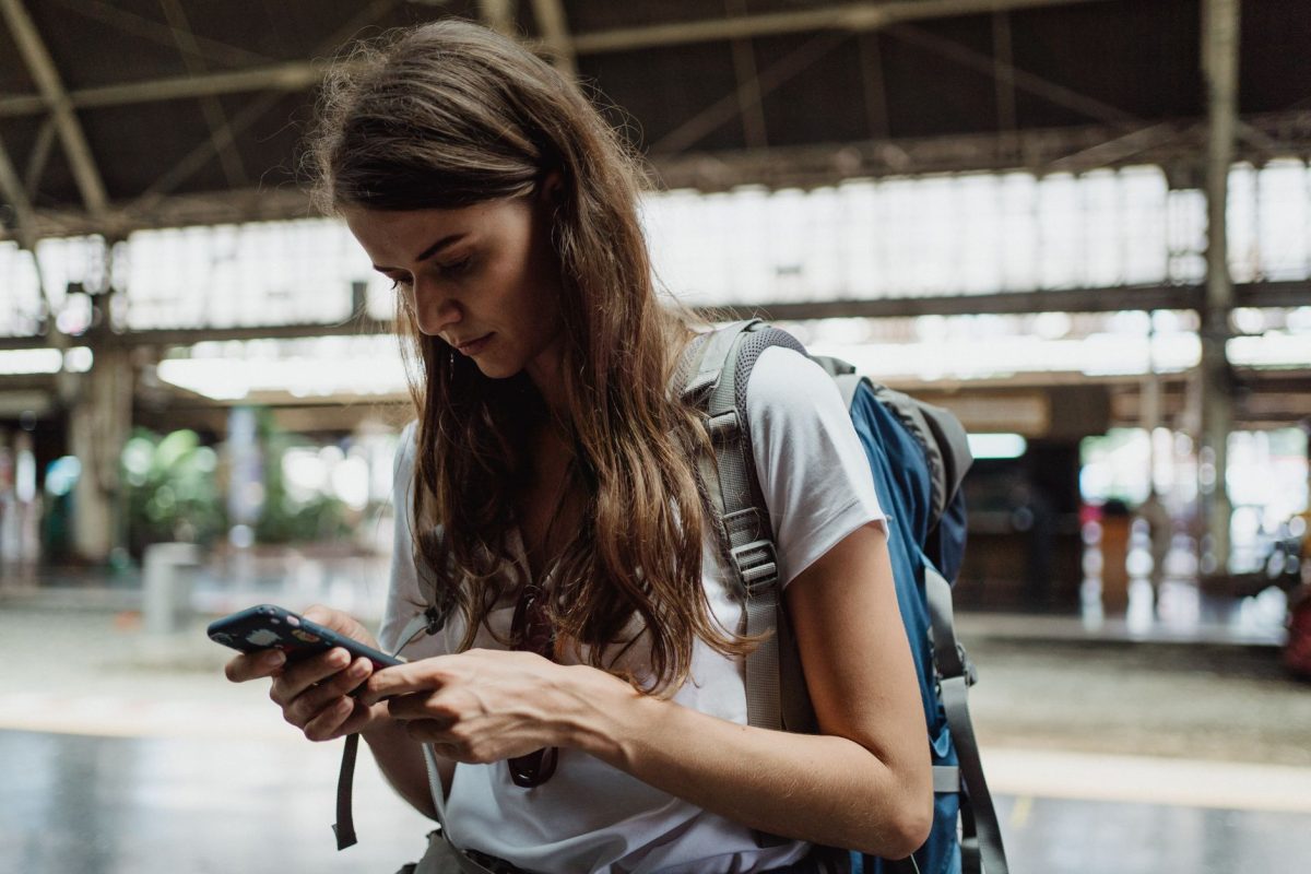 5 Transit Transfer Moves That Help City Visitors Skip the Worst Waits 1 A young woman checks her smartphone while traveling at a train station.