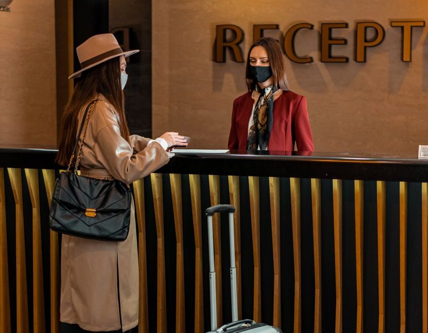 5 Luggage Storage Moves That Can Rescue the Awkward Last Day of a Trip 1 Businesswoman checking into a hotel at a stylish reception desk, engaging with staff.