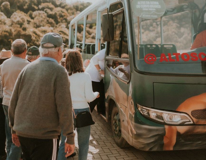 5 National Park Shuttle Snags That Can Burn Half Your Day Trip 5 Group of people boarding a bus surrounded by nature, showcasing travel and transportation.