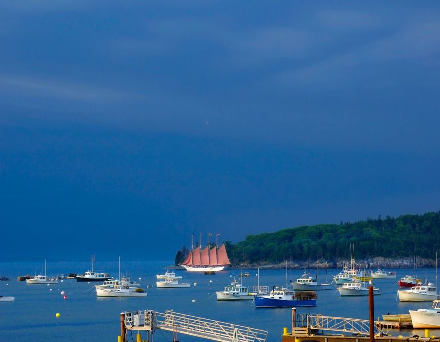 A scenic view of Bar Harbor&amp;amp;#39;s boats and coastline under a dramatic overcast sky.