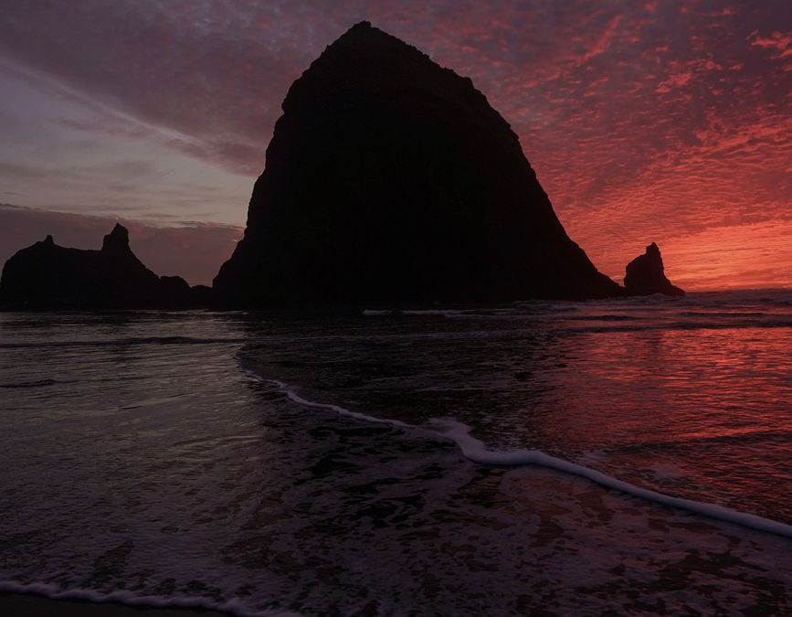 Silhouette of Haystack Rock at sunset on Cannon Beach, Oregon, USA. Perfect travel and nature inspiration.