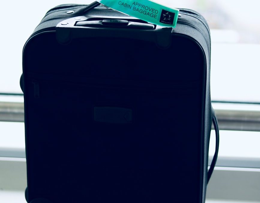 Close up of a black suitcase with a cabin approved tag in airport setting.