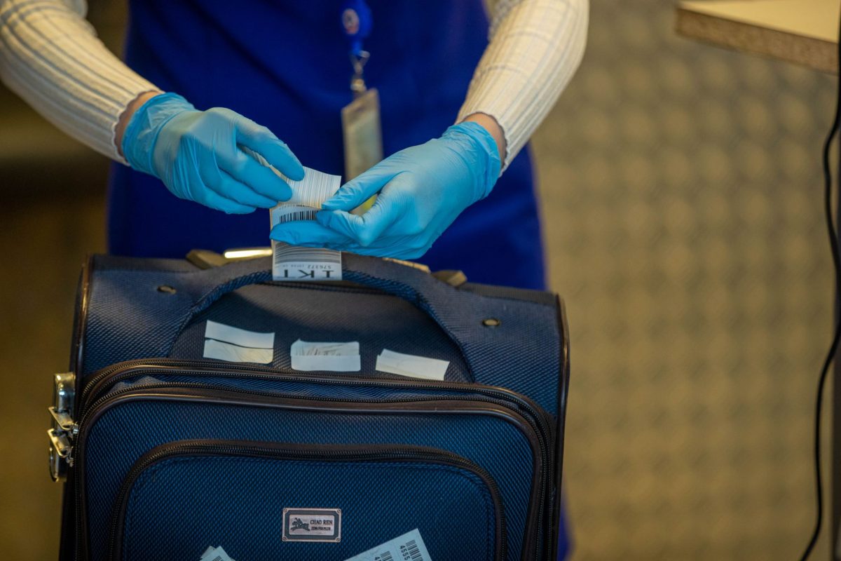 Close up of airport security process with gloved hands inspecting luggage tags.