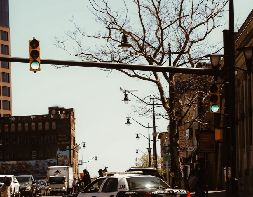 A Newark police car navigating an urban street with traffic lights and buildings.