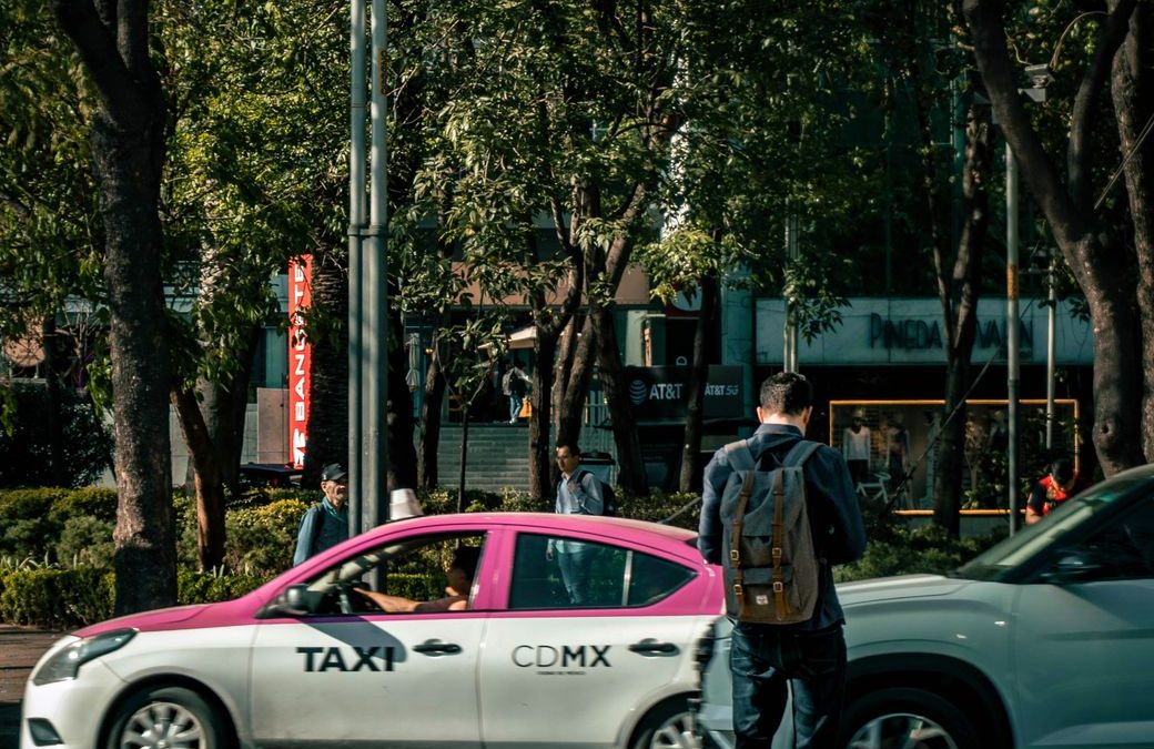 A bustling city street in Ciudad de México featuring a CDMX taxi and pedestrian.