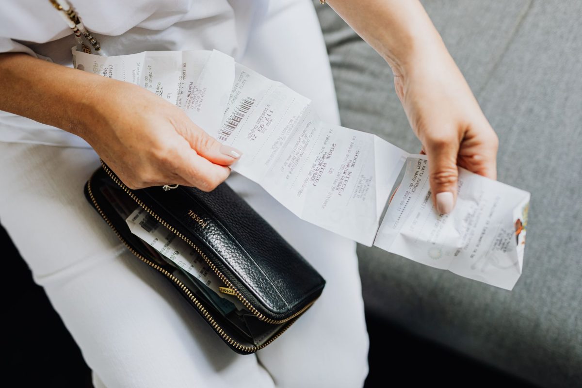 Close up of a woman&amp;#39;s hands managing multiple receipts taken from a black wallet.