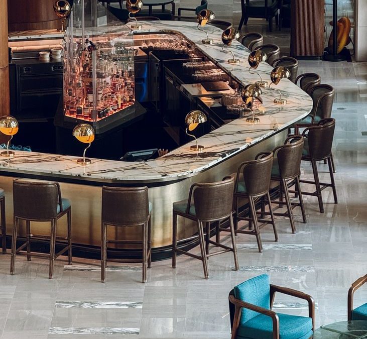 Elegant hotel lobby with a stylish curved bar and seating area, featuring modern decor.