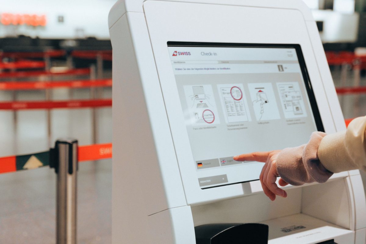Passenger using self service check in kiosk at airport for convenient travel experience.