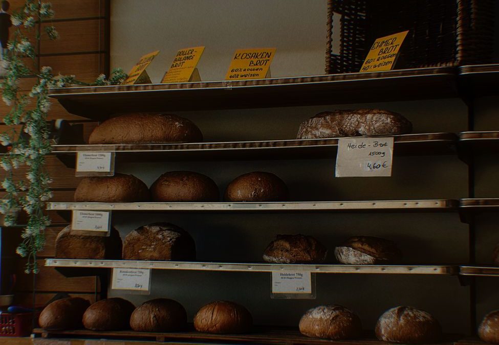 A variety of freshly baked bread displayed on rustic shelves in a cozy bakery.