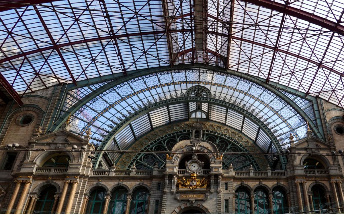 Grand interior of Antwerp Central Station with intricate architectural details and glass ceiling.