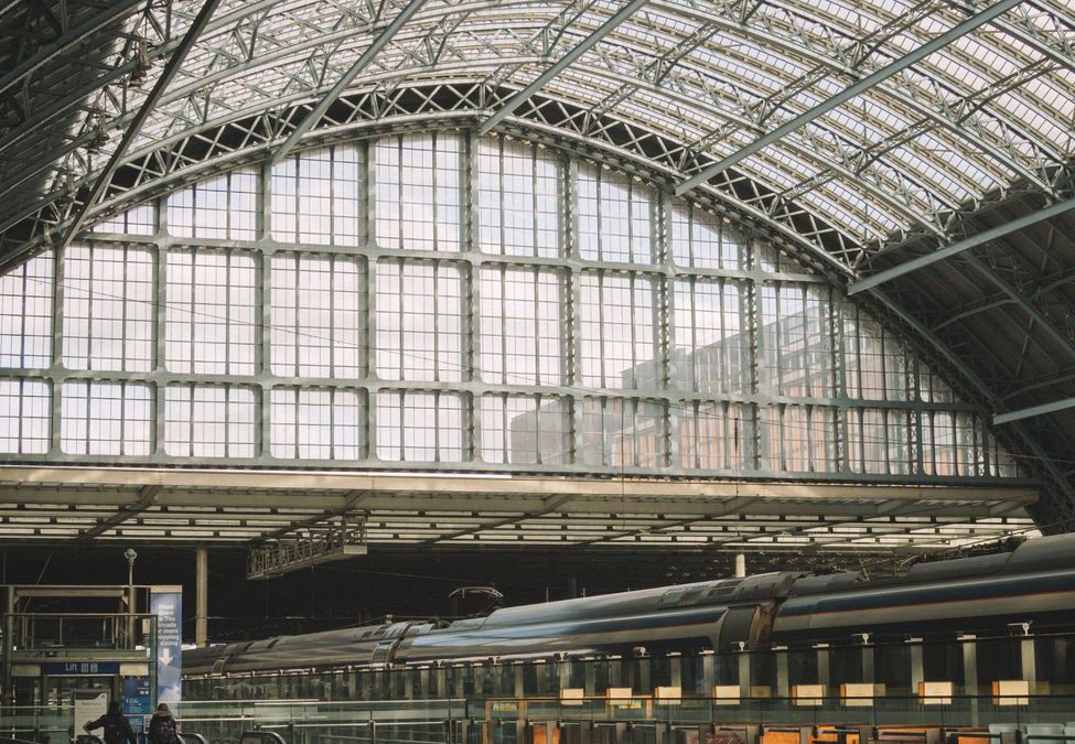 Spacious indoor view of a train station with glass panels and steel frame.