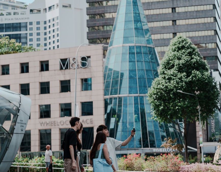 Group of tourists taking a selfie in front of modern city architecture.