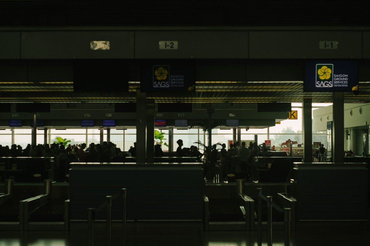 5 Bag Drop Details Travelers Often Learn Too Late at the Airport 5 Silhouetted travelers wait at a bustling airport check in counter, showcasing Saigon Ground Services.