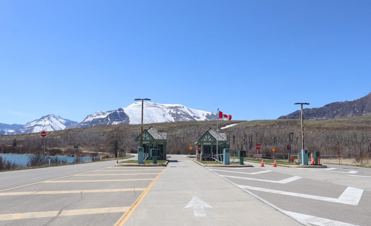 Canadian border crossing amidst stunning snow capped mountains and clear blue sky.