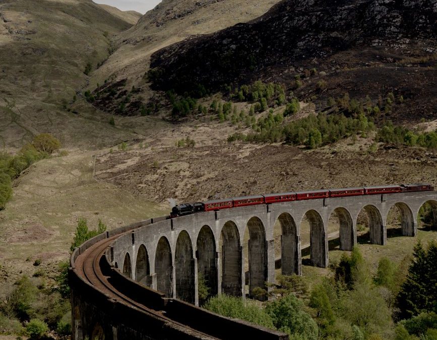 Train crosses the famous viaduct amidst scenic mountains and lush valley.