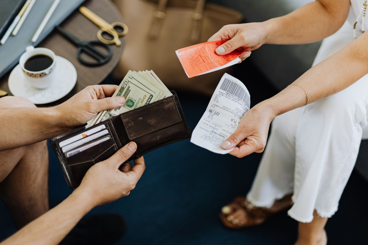 Close up of a financial transaction involving cash and receipts over a coffee table.