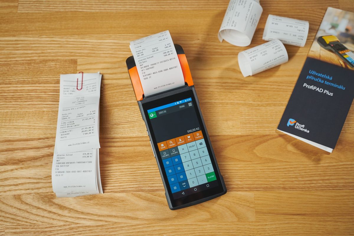 Electronic payment terminal with receipts, showcasing modern transaction processing on a wooden desk.