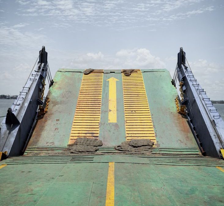 A green ramp of a landing craft with a yellow arrow directs vessels.