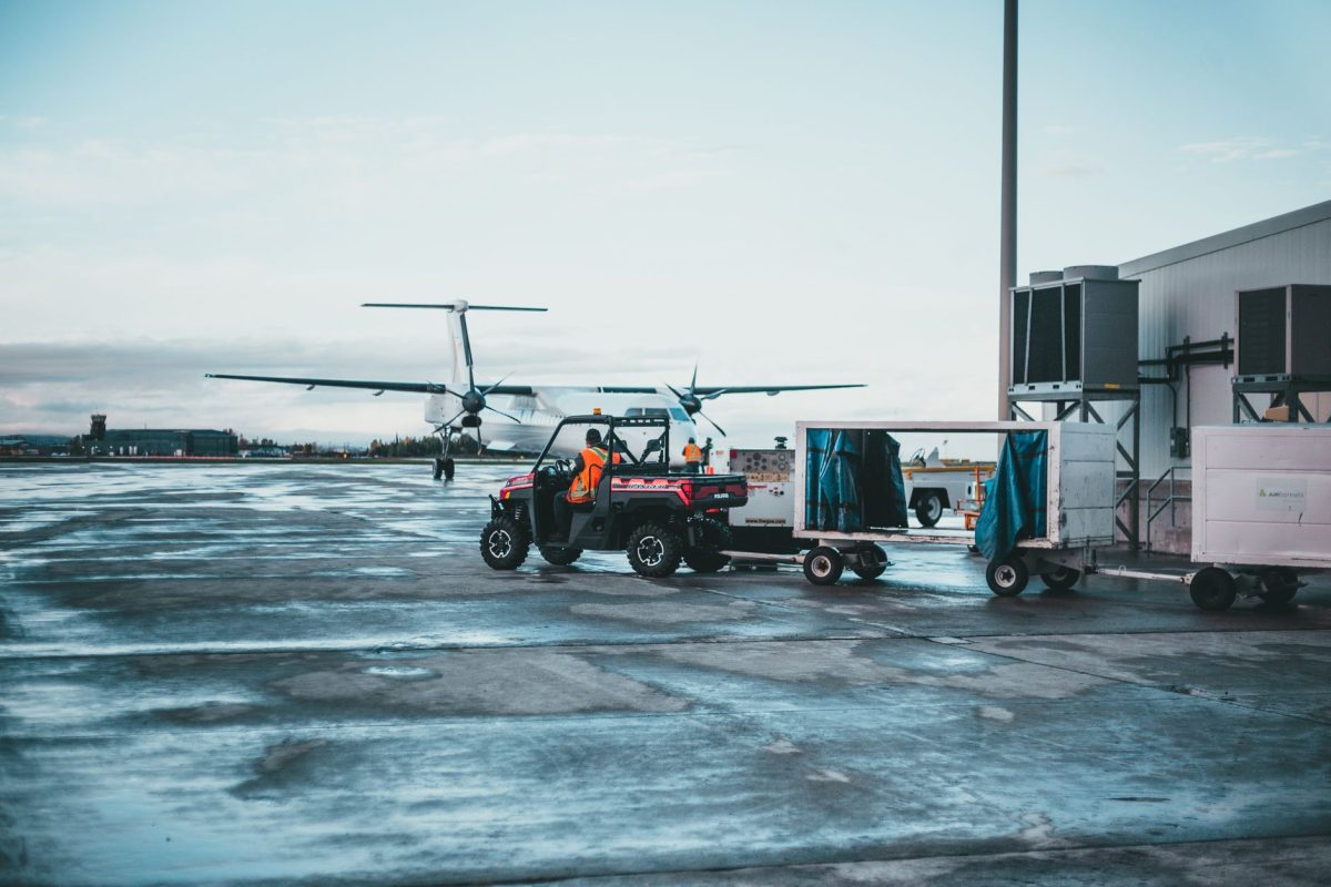 View of airport crew managing luggage near airplane at dawn.