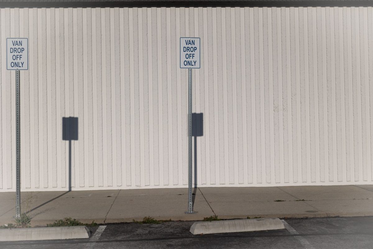 Van drop off only zone in an urban parking area with shadows and signs.
