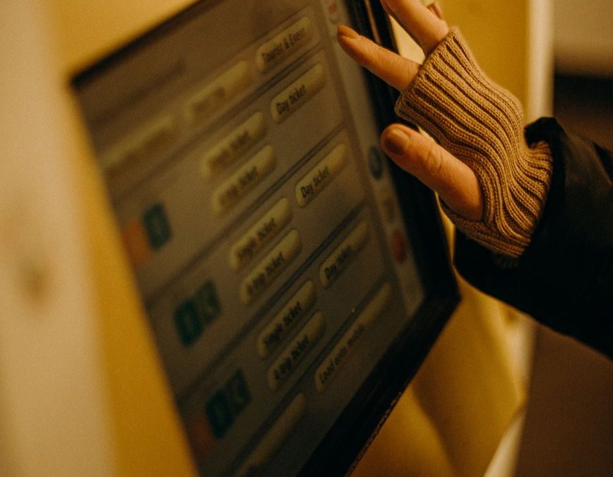 A close up image of a gloved hand operating a Berlin U Bahn ticket machine showing electronic interface and selection buttons.