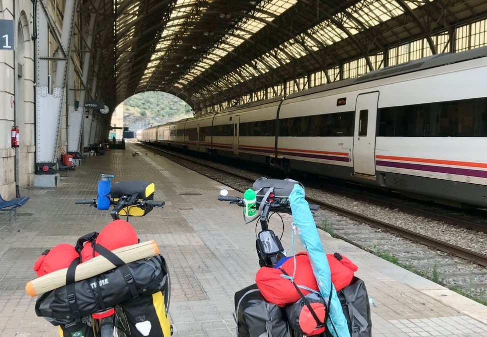 Loaded touring bikes in a picturesque European train station, ready for travel.