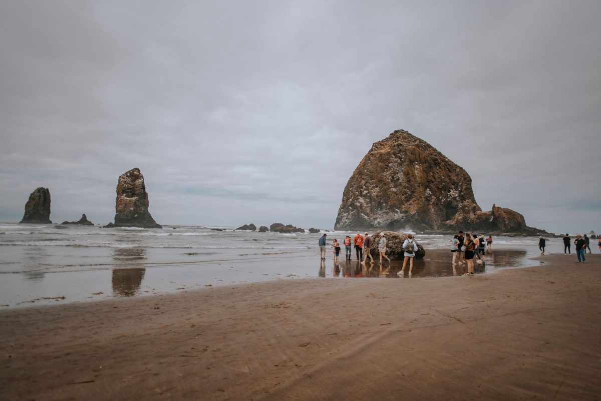 A group of tourists explore Haystack Rock at Cannon Beach, Oregon.