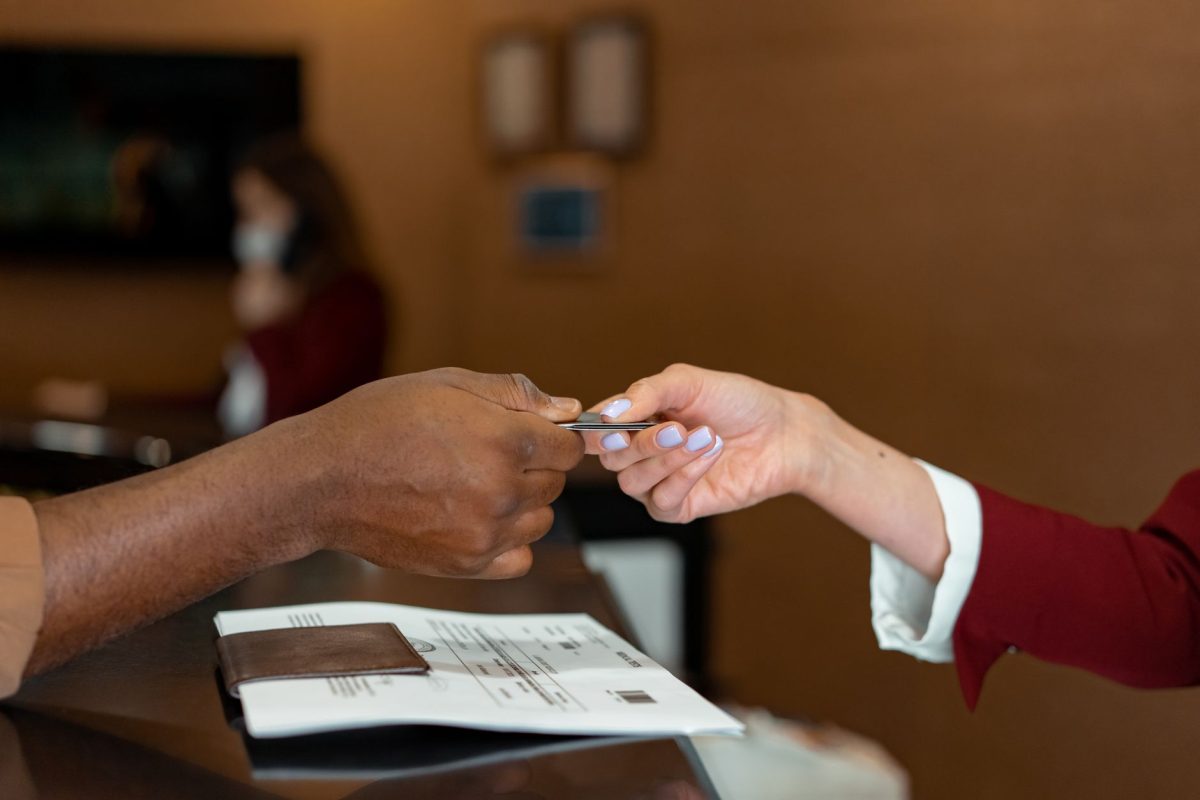 Close up of a hotel receptionist receiving a credit card from a guest, highlighting a transaction at check in.