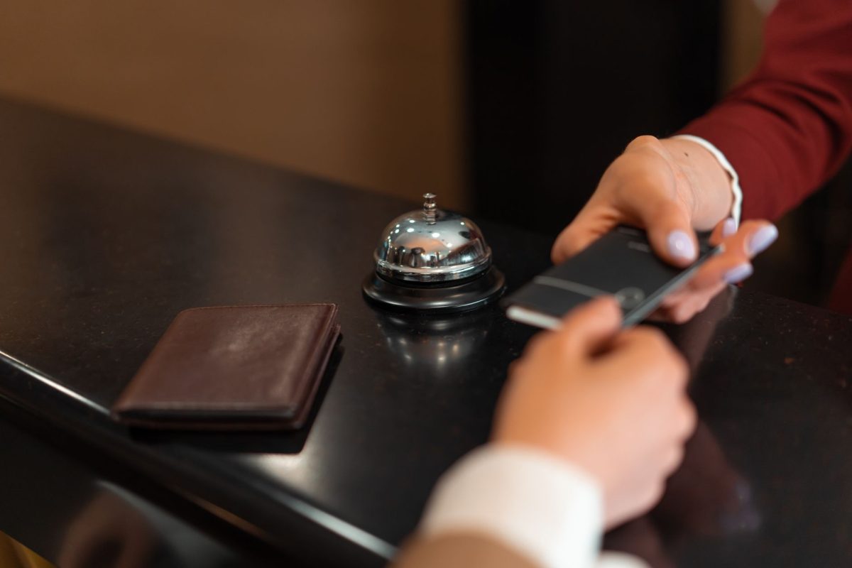 A close up of a hotel check in process with a smartphone and card transaction at the reception desk.