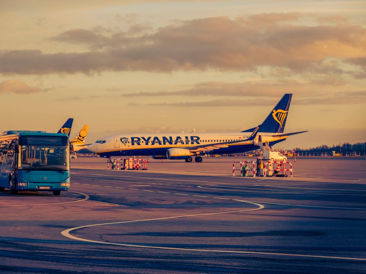 Ryanair aircraft parked at Wrocław airport during sunset, with a shuttle bus in view.